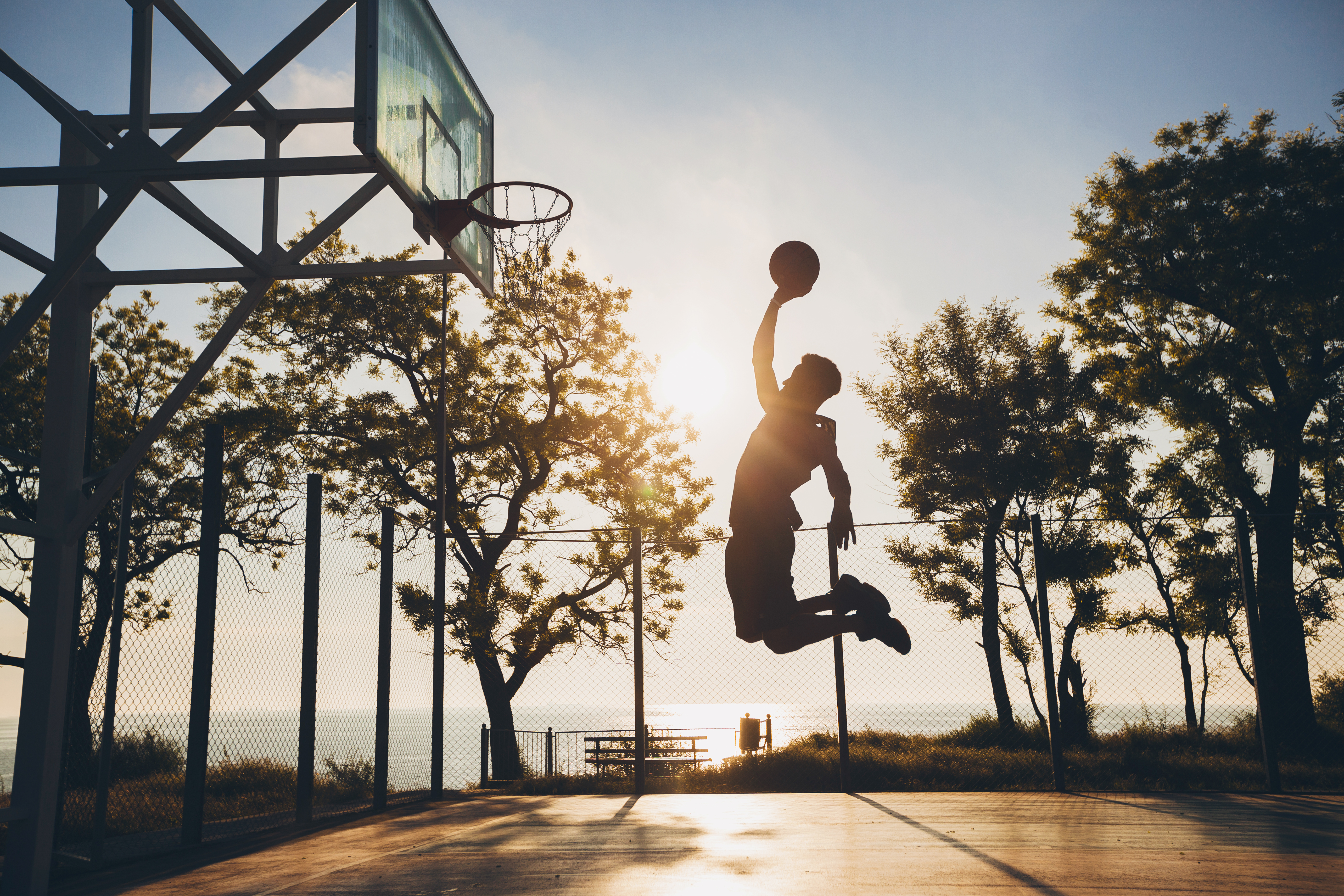 Basketball player jumping silhouette at sunrise